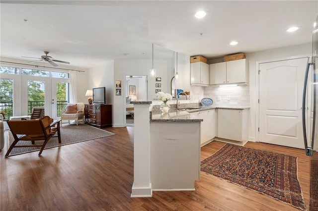 kitchen with white cabinets, sink, hardwood / wood-style flooring, ceiling fan, and kitchen peninsula