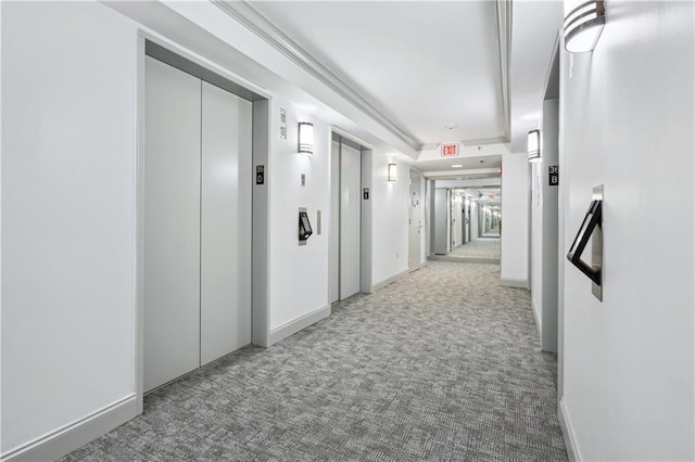 hallway with elevator and light colored carpet