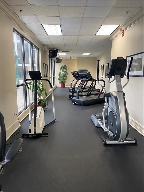 exercise room with a paneled ceiling and crown molding