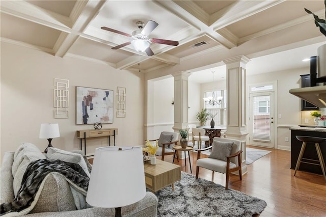 living room featuring ornate columns, coffered ceiling, ceiling fan with notable chandelier, beam ceiling, and wood-type flooring