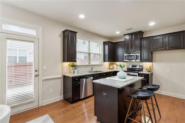 kitchen featuring appliances with stainless steel finishes, a kitchen breakfast bar, sink, a center island, and light hardwood / wood-style floors