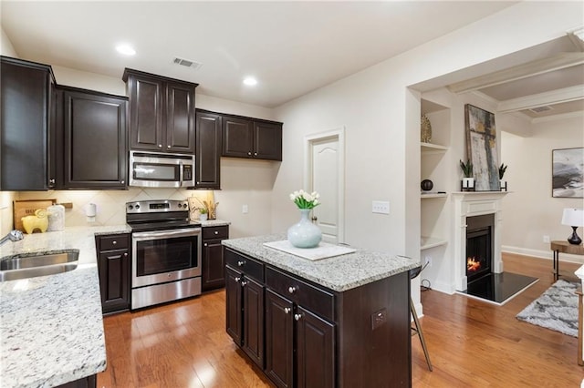 kitchen featuring hardwood / wood-style floors, a kitchen breakfast bar, a center island, and stainless steel appliances