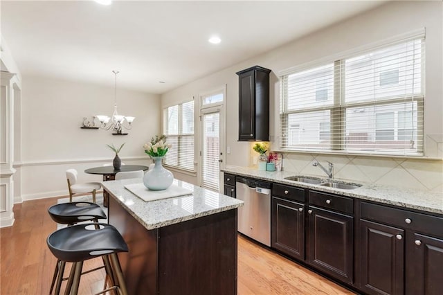 kitchen featuring sink, tasteful backsplash, stainless steel dishwasher, light hardwood / wood-style floors, and a kitchen island