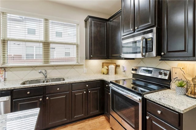 kitchen featuring backsplash, sink, light wood-type flooring, dark brown cabinetry, and stainless steel appliances