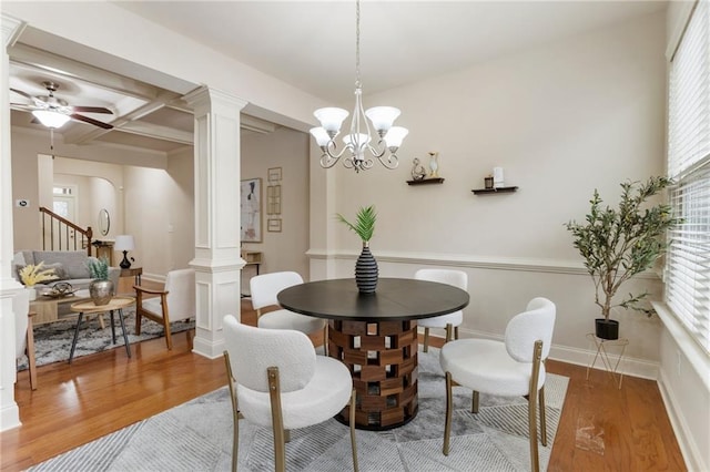 dining room with wood-type flooring, ceiling fan with notable chandelier, ornate columns, and coffered ceiling