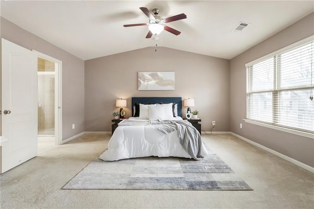 bedroom featuring ceiling fan, vaulted ceiling, light colored carpet, and ensuite bath