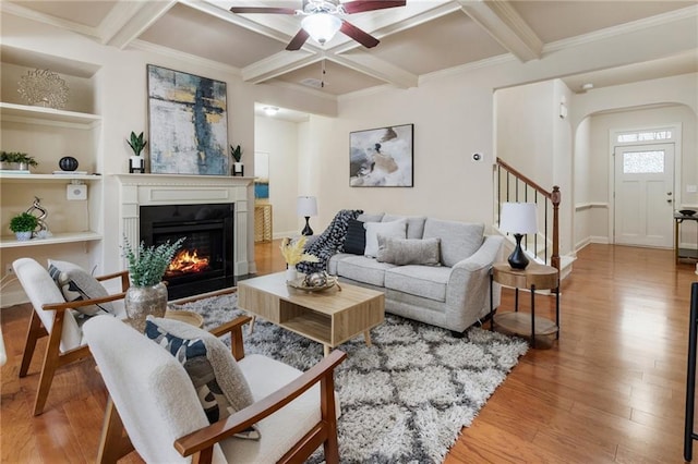 living room with coffered ceiling, ceiling fan, beam ceiling, wood-type flooring, and built in features