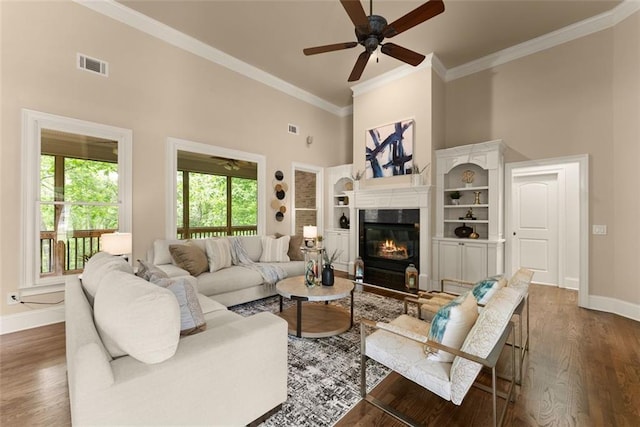 living area featuring visible vents, baseboards, ceiling fan, and a high ceiling