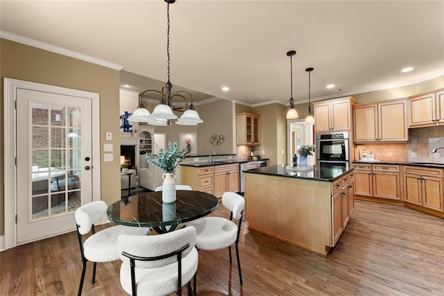 kitchen with crown molding, appliances with stainless steel finishes, a center island, wood finished floors, and a sink