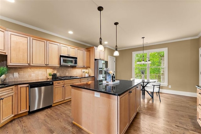 kitchen with appliances with stainless steel finishes, decorative backsplash, wood finished floors, a kitchen island, and ornamental molding