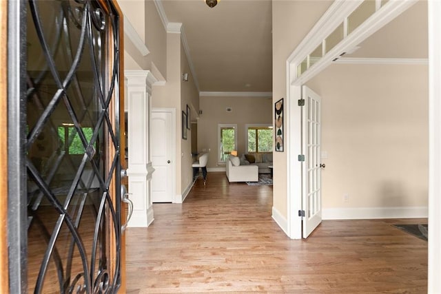 entrance foyer with light wood-style floors, ornamental molding, and baseboards