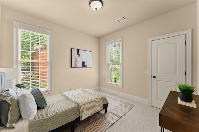 carpeted bedroom with baseboards, multiple windows, and visible vents