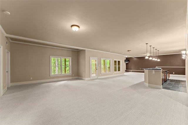 unfurnished living room featuring crown molding, baseboards, carpet floors, and a healthy amount of sunlight