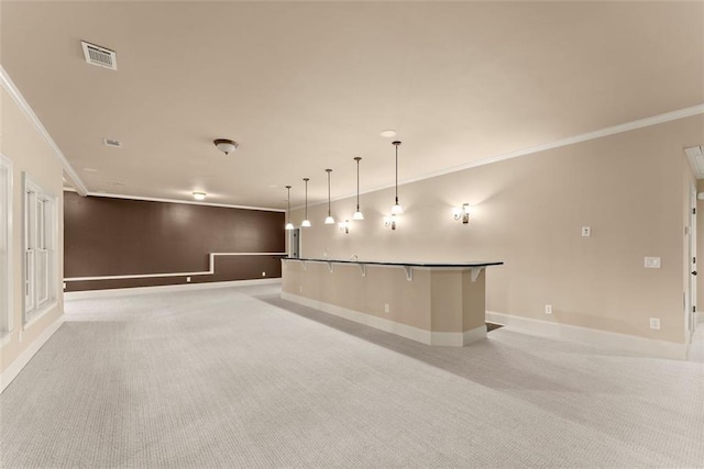 unfurnished living room featuring visible vents, baseboards, a bar, ornamental molding, and light carpet