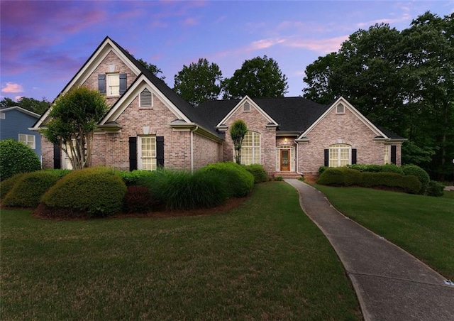 traditional-style house featuring brick siding and a front lawn