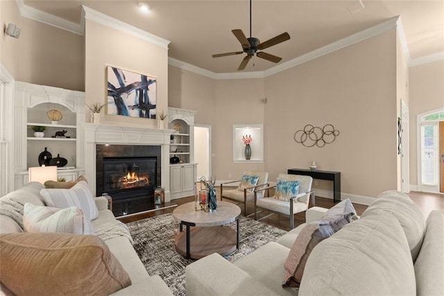living room with ceiling fan, wood finished floors, baseboards, ornamental molding, and a premium fireplace