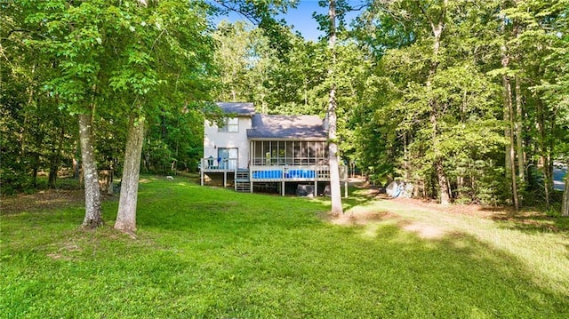 rear view of house featuring a sunroom, a yard, and a deck