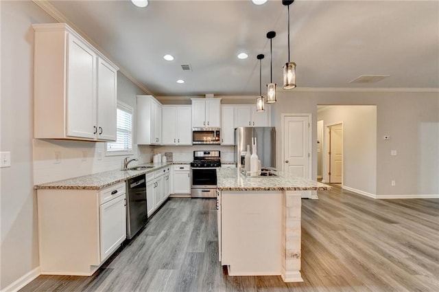 kitchen with crown molding, a center island, hanging light fixtures, appliances with stainless steel finishes, and white cabinets