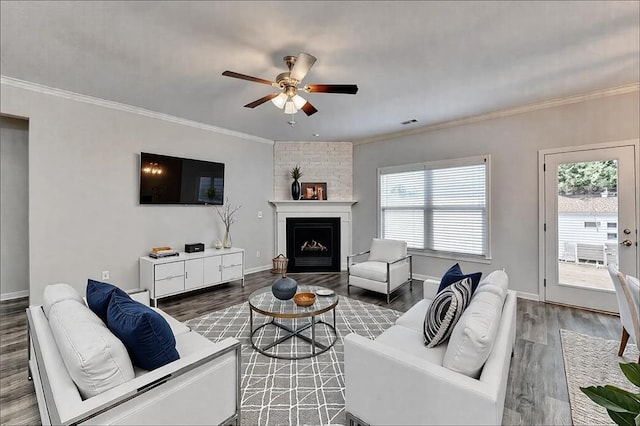 living room with crown molding, hardwood / wood-style floors, ceiling fan, and a fireplace