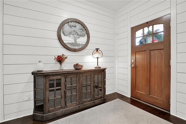 foyer entrance with dark hardwood / wood-style flooring, crown molding, and wood walls