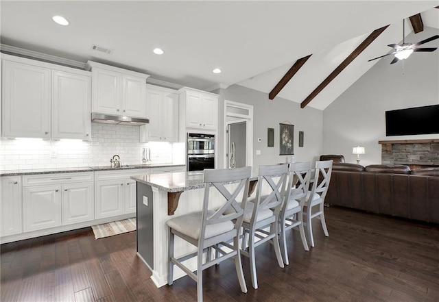 kitchen with white cabinets, beam ceiling, tasteful backsplash, and a kitchen island