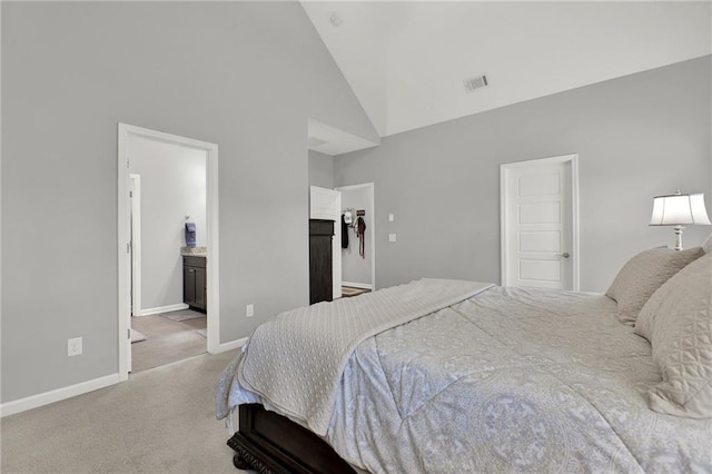 bedroom with ensuite bath, light carpet, and high vaulted ceiling