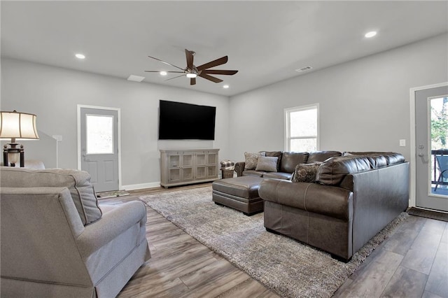 living room featuring light wood-type flooring, plenty of natural light, and ceiling fan