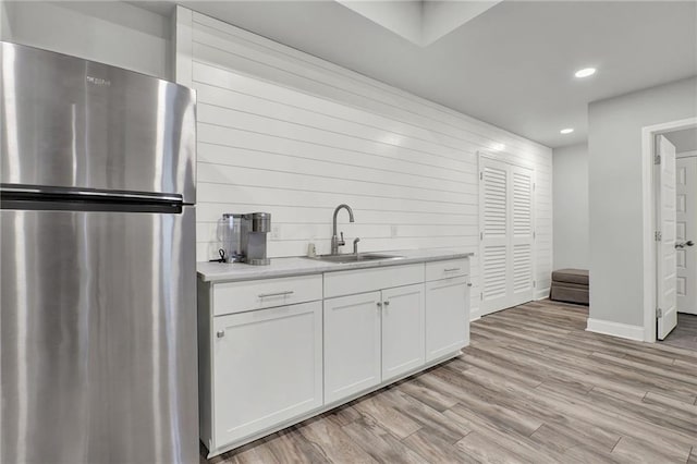 kitchen featuring stainless steel refrigerator, sink, white cabinets, and light hardwood / wood-style floors