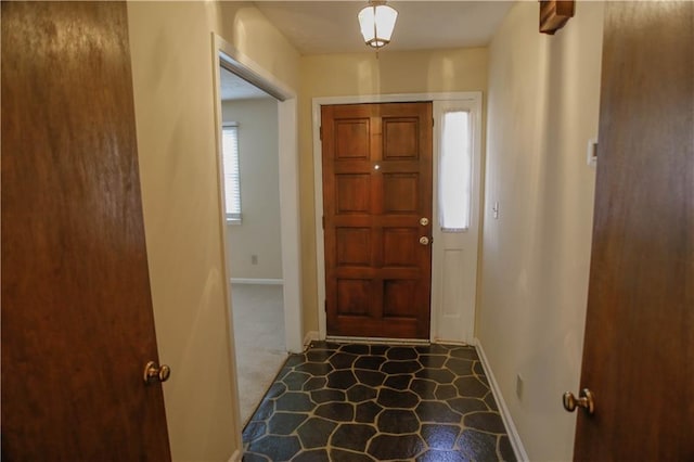 foyer entrance with baseboards and carpet floors