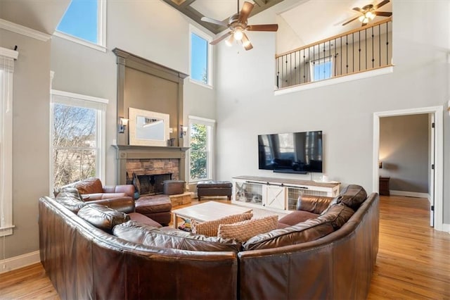 living room with ceiling fan, a fireplace, and light wood-type flooring