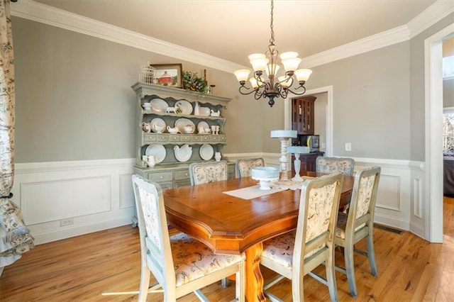 dining area with an inviting chandelier, crown molding, and light hardwood / wood-style flooring