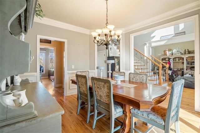 dining area with ornamental molding, a chandelier, and light hardwood / wood-style floors