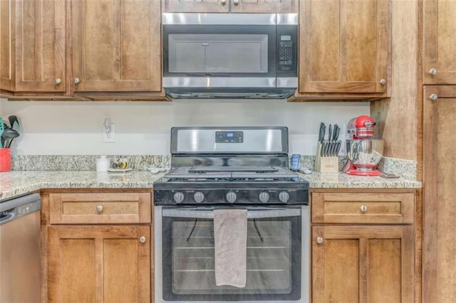 22 Gowen Dr, Rome, GA 30165 - kitchen with stainless steel appliances, brown cabinetry, and light stone counters