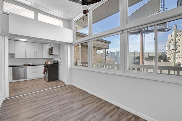 kitchen featuring tasteful backsplash, a healthy amount of sunlight, white cabinets, and stainless steel appliances