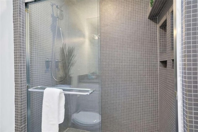 bathroom featuring toilet and a shower with shower door