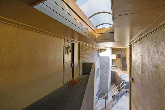 hall with brick wall and wood-type flooring