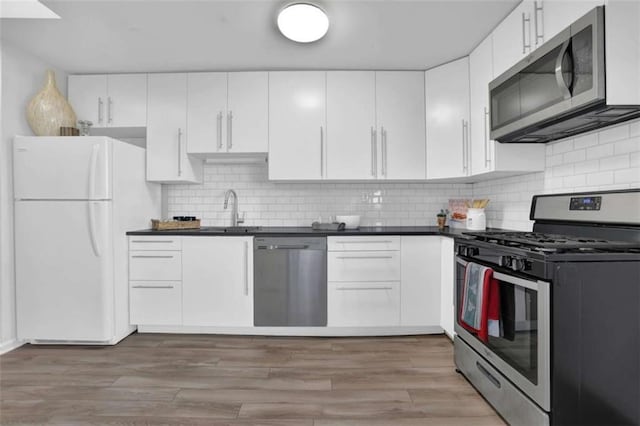 kitchen with tasteful backsplash, sink, white cabinets, and appliances with stainless steel finishes