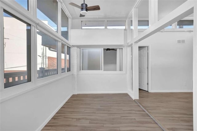 unfurnished sunroom with ceiling fan