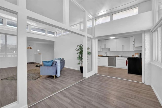 living room with sink, a high ceiling, and light hardwood / wood-style flooring