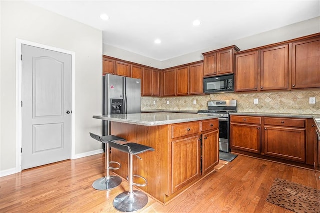 2625 Blackstock Dr, Cumming, GA 30041 - kitchen featuring stainless steel appliances, a breakfast bar, backsplash, wood finished floors, and a center island