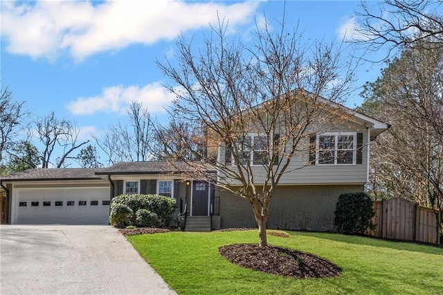 split level home featuring driveway, fence, a front yard, a garage, and brick siding