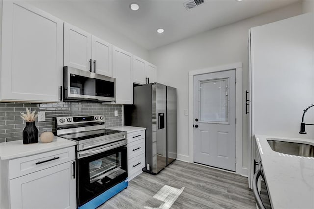 543 Paines Ave NW, Atlanta, GA 30318 - kitchen with visible vents, appliances with stainless steel finishes, light stone counters, white cabinetry, and a sink