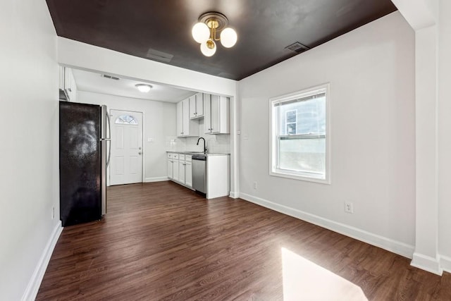 kitchen featuring sink, dark wood-type flooring, appliances with stainless steel finishes, white cabinetry, and tasteful backsplash