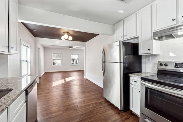 kitchen featuring appliances with stainless steel finishes, dark hardwood / wood-style floors, white cabinetry, decorative backsplash, and light stone counters