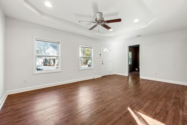 spare room with dark wood-type flooring, ceiling fan, and a raised ceiling