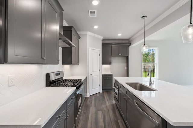 kitchen featuring appliances with stainless steel finishes, sink, pendant lighting, and a center island with sink