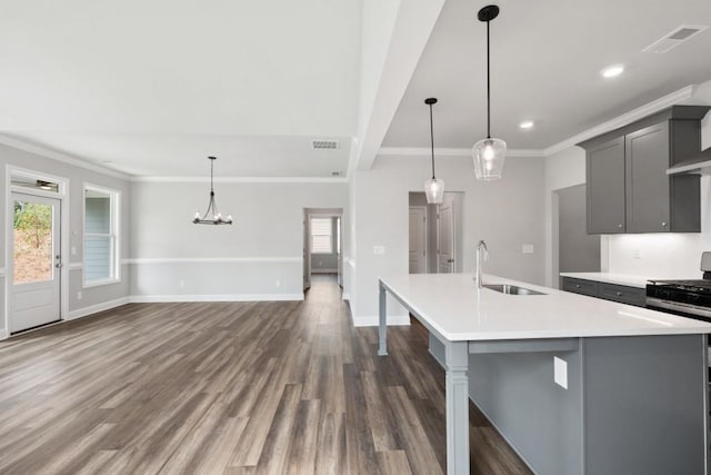 kitchen with a kitchen island with sink, gray cabinetry, sink, stainless steel gas range, and pendant lighting