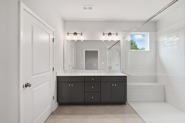 bathroom with vanity, a tile shower, and tile patterned floors