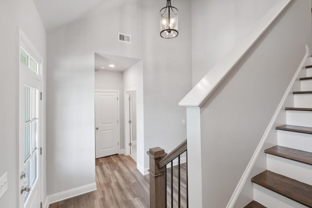 interior space featuring light wood-type flooring, high vaulted ceiling, and a chandelier