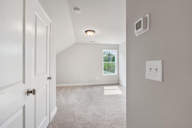 additional living space featuring vaulted ceiling and light carpet